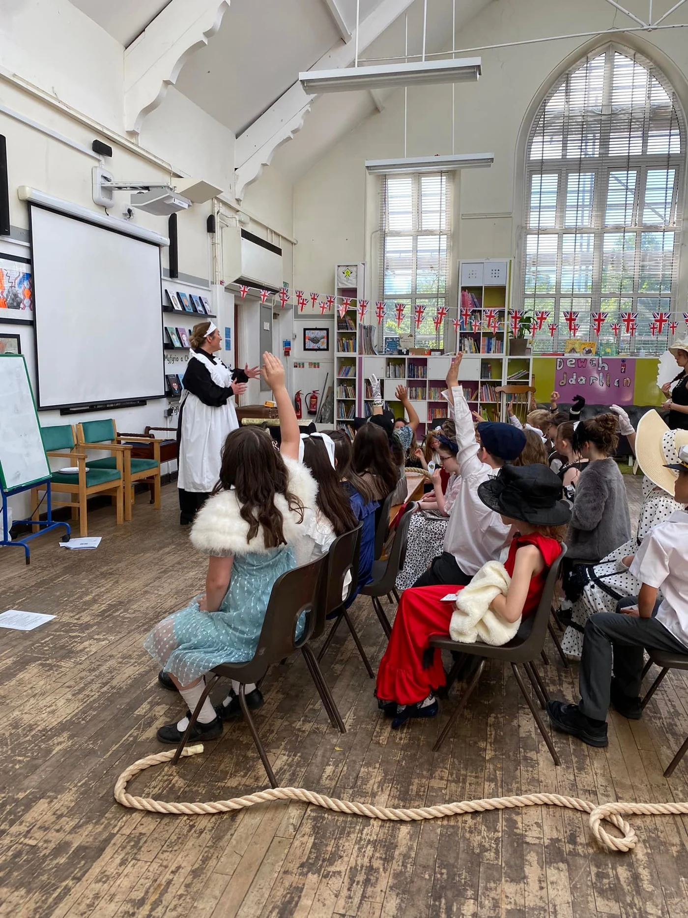 Pupils raising their hands as a Histoire performer in a Titanic stewardess costume leads an interactive school session