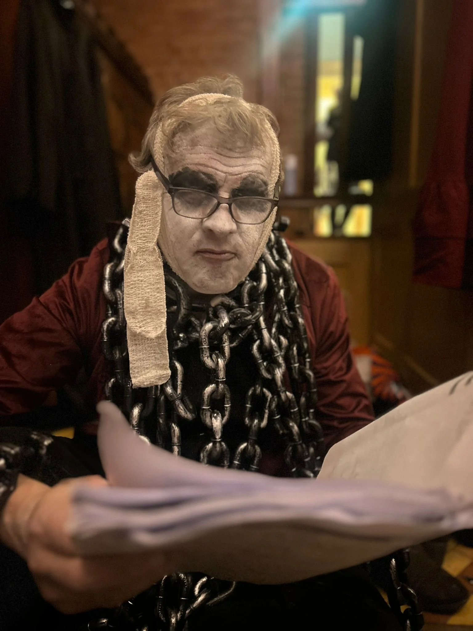 Scrooge in costume at the dining table